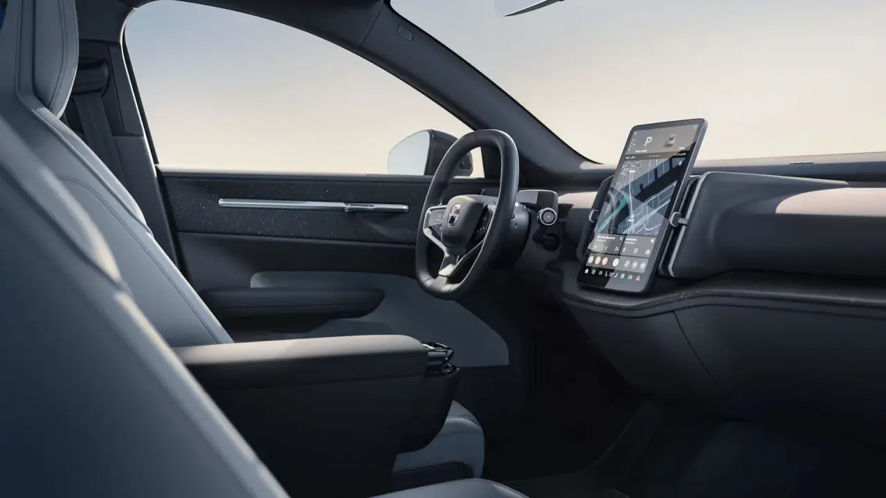 Interni minimalisti del Volvo EX30: sedili chiari, volante moderno e grande schermo centrale con navigazione.