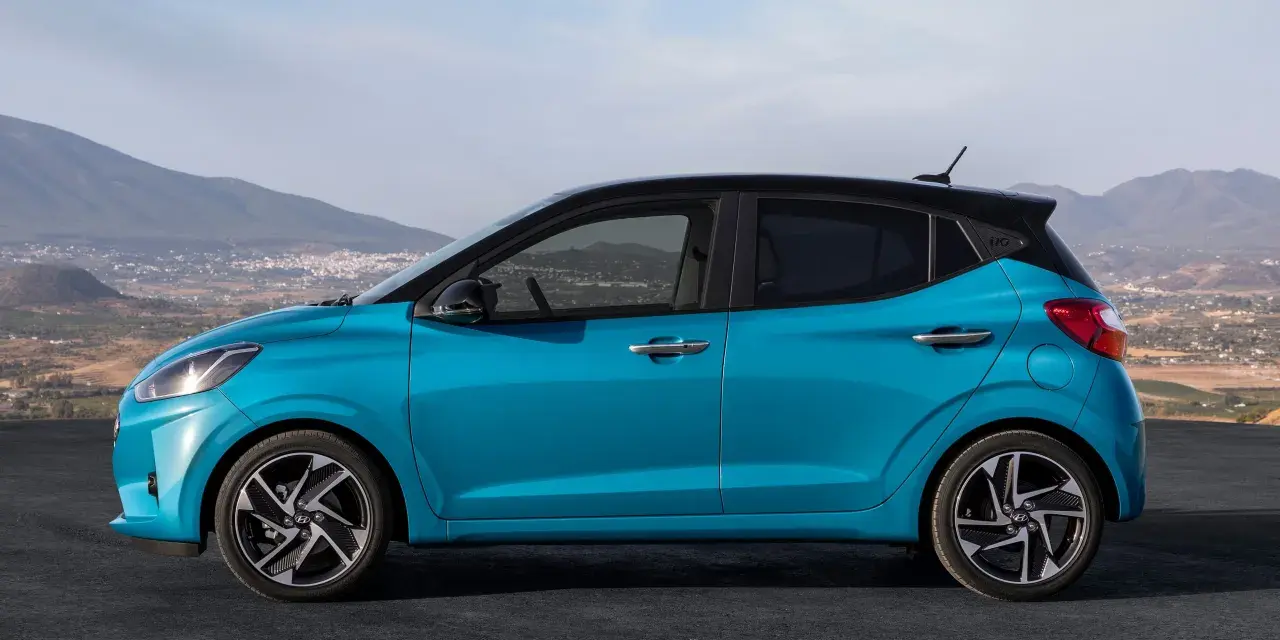 Hyundai i10 blu con tetto nero, vista laterale. Le dimensioni compatte la rendono perfetta per la città.
