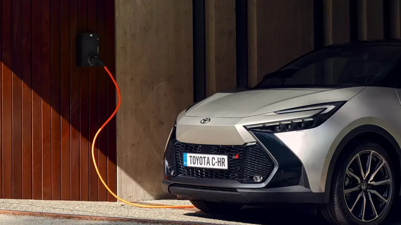 Toyota C-HR GR in argento, con cavo arancione collegato alla stazione di ricarica. L'auto plug-in è pronta per la sua prossima avventura.