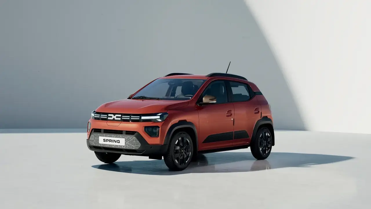 Dacia Spring, un'auto elettrica arancione, pronta per un viaggio in autostrada con la sua autonomia.