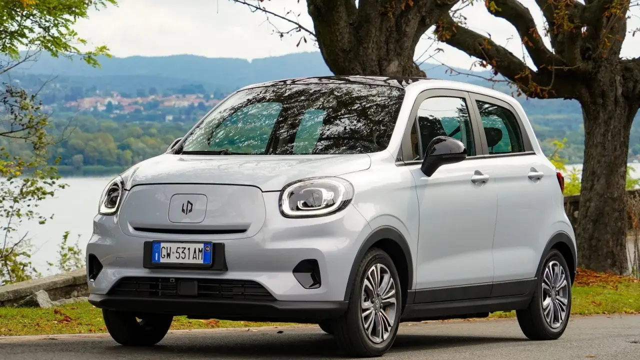 Leapmotor T03, un'auto elettrica grigia parcheggiata vicino a un lago, pronta per un viaggio con la sua eccellente autonomia.