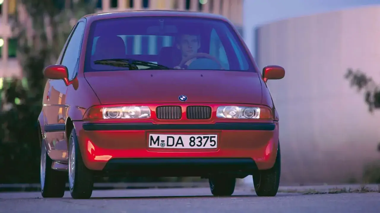 La BMW E1 rossa, un prototipo elettrico, si presenta con un design compatto e futuristico, pronta a sfrecciare nel traffico urbano.