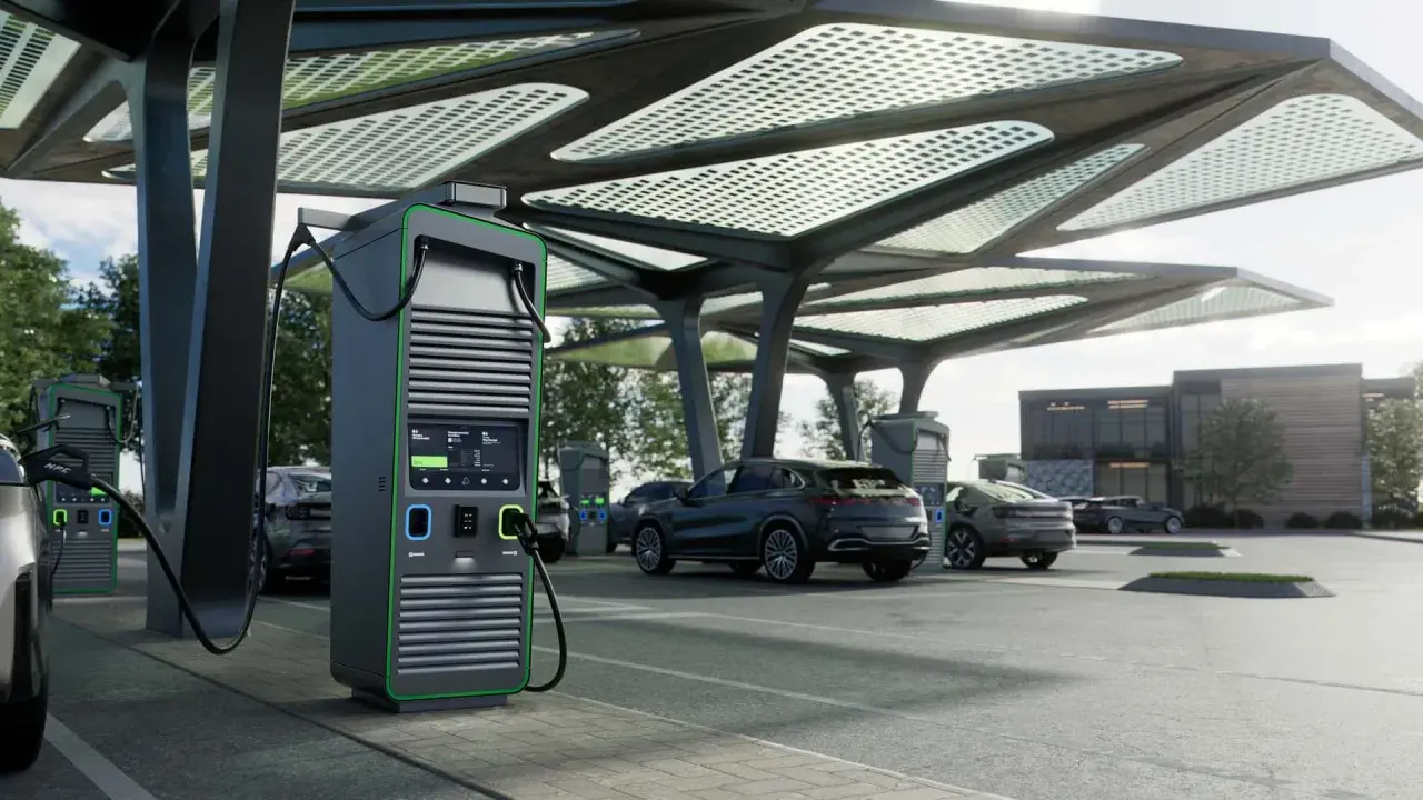 Moderne colonnine ricarica auto elettriche sotto una pensilina con pannelli solari. Diverse auto in carica.