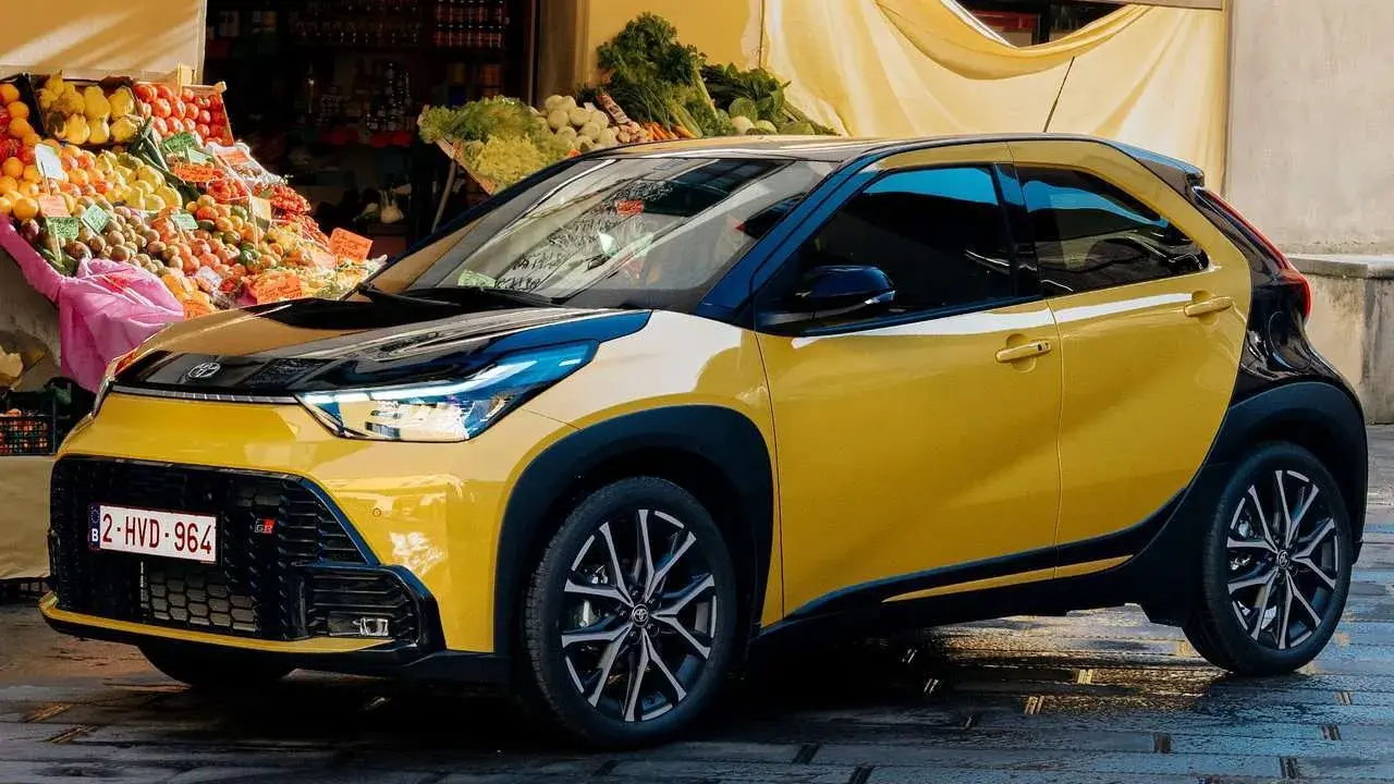 Toyota Aygo X gialla parcheggiata davanti a un mercato. Nessun problema visibile, solo un'auto elegante.