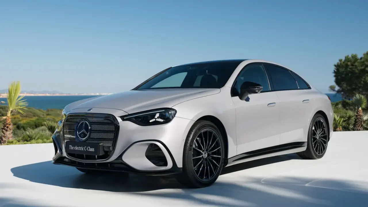 La Mercedes Classe C 2026, un'elegante berlina elettrica, si presenta con un design moderno e sportivo, con cerchi neri e uno sfondo marino.