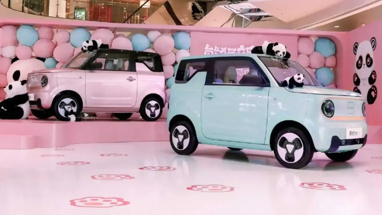 Due Geely Panda rosa e azzurra, circondate da palloncini e peluche di panda, in un allestimento a tema.