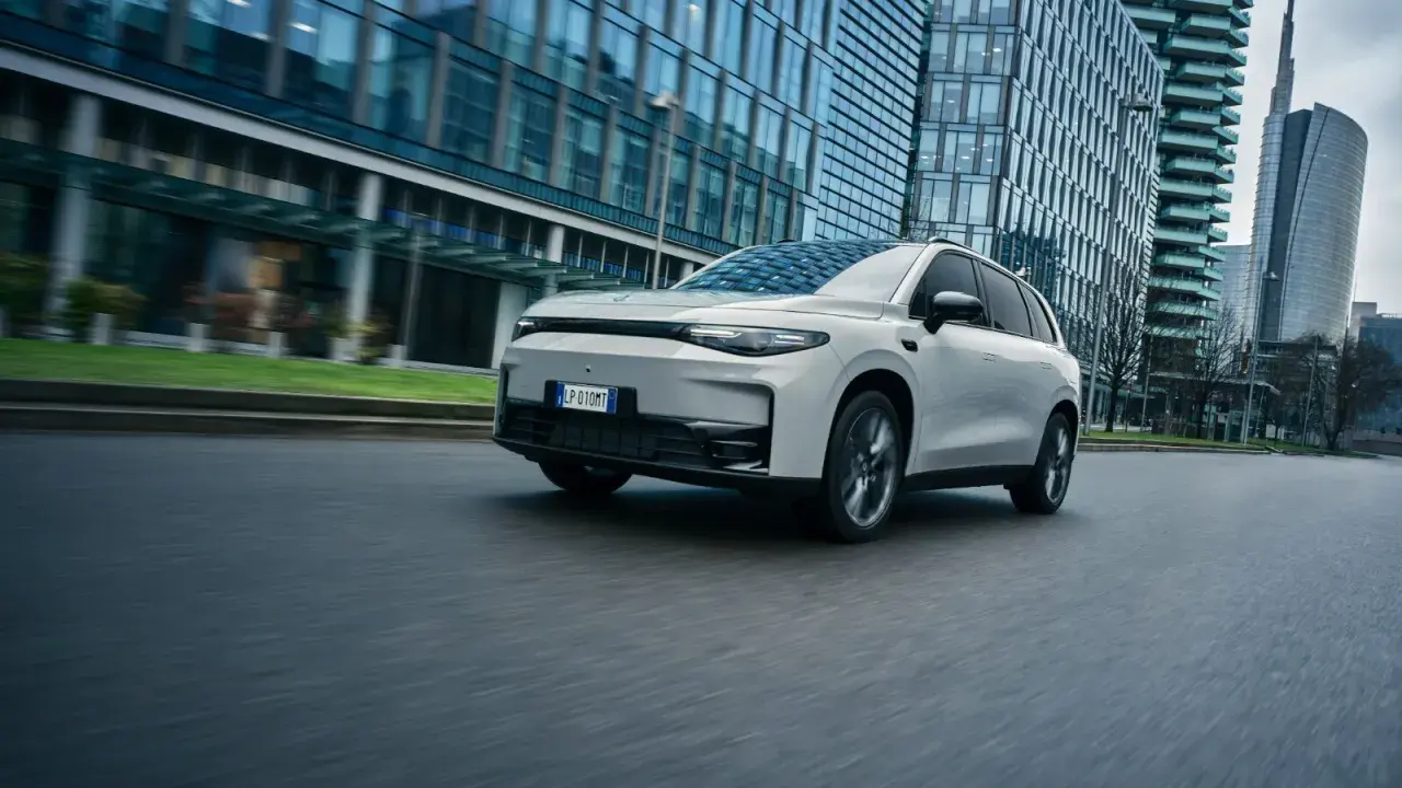 La Leapmotor C10 REEV sfreccia su strada, circondata da moderni grattacieli.