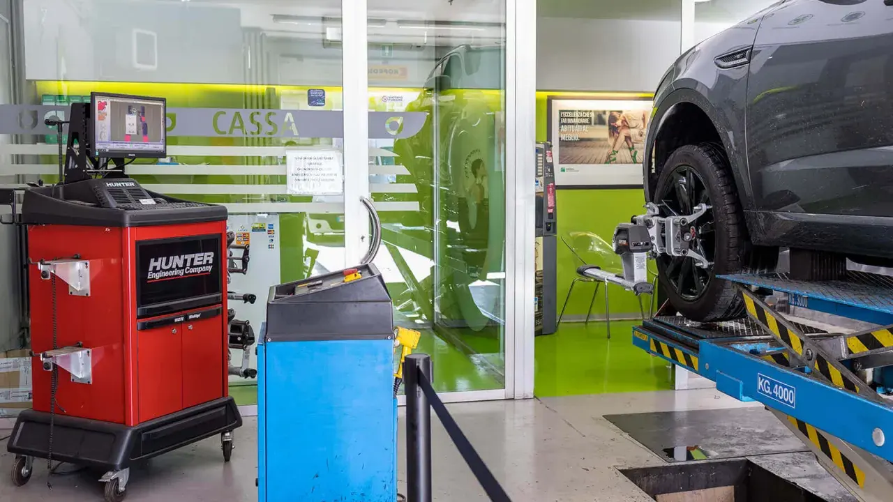 Attrezzatura per la convergenza auto in officina. Un'auto è sollevata su un ponte, con sensori applicati alla ruota.