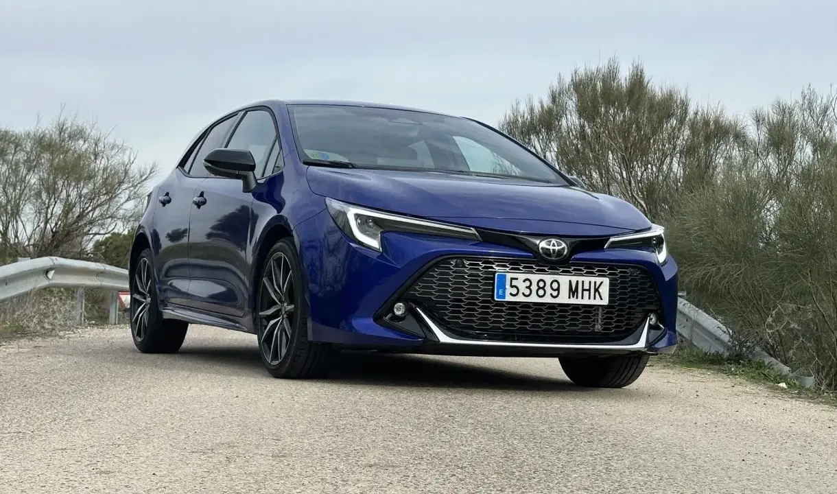 Toyota Corolla blu parcheggiata su strada sterrata, con vegetazione sullo sfondo. Un'auto che offre diverse motorizzazioni.