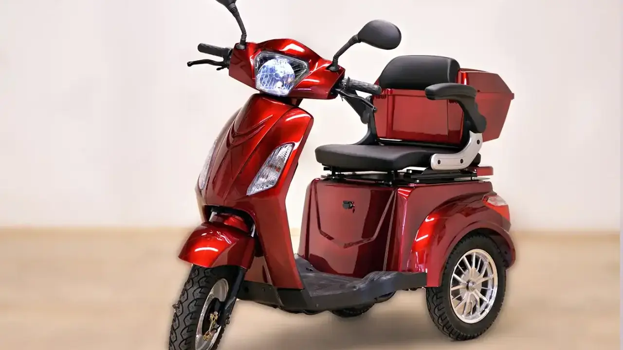 Un'auto elettrica a 3 ruote, rossa metallizzata, con sedile comodo e bauletto posteriore. Ideale per muoversi in città con stile e praticità.
