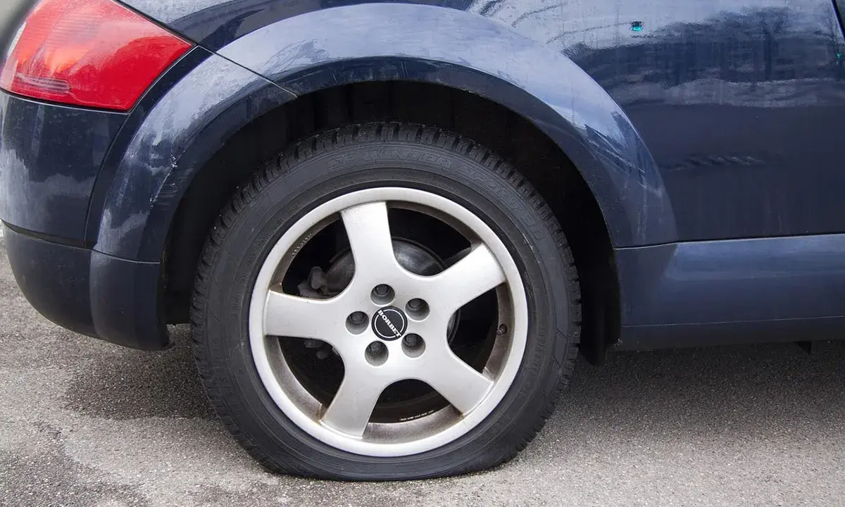 Ruota posteriore di un'auto blu con evidente perdita pressione pneumatici. Il coprimozzo riporta il logo "Borbet".