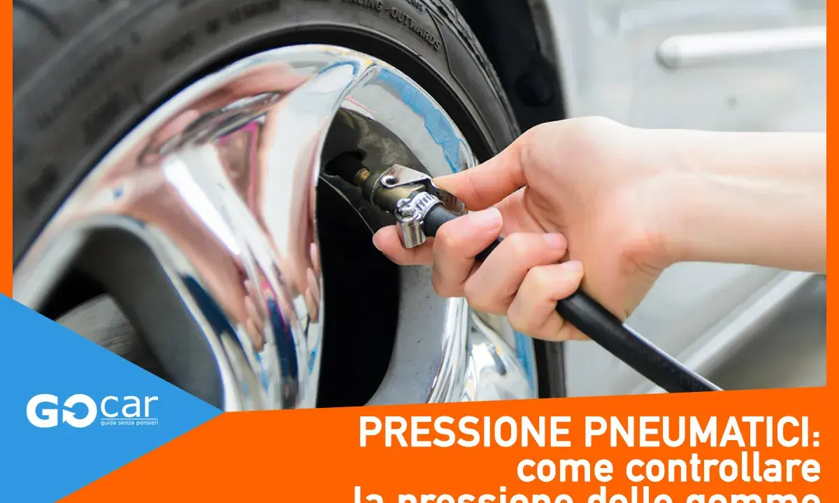Controllo gomme auto: una mano collega il tubo di un compressore alla valvola di un pneumatico cromato. Essenziale per la sicurezza.
