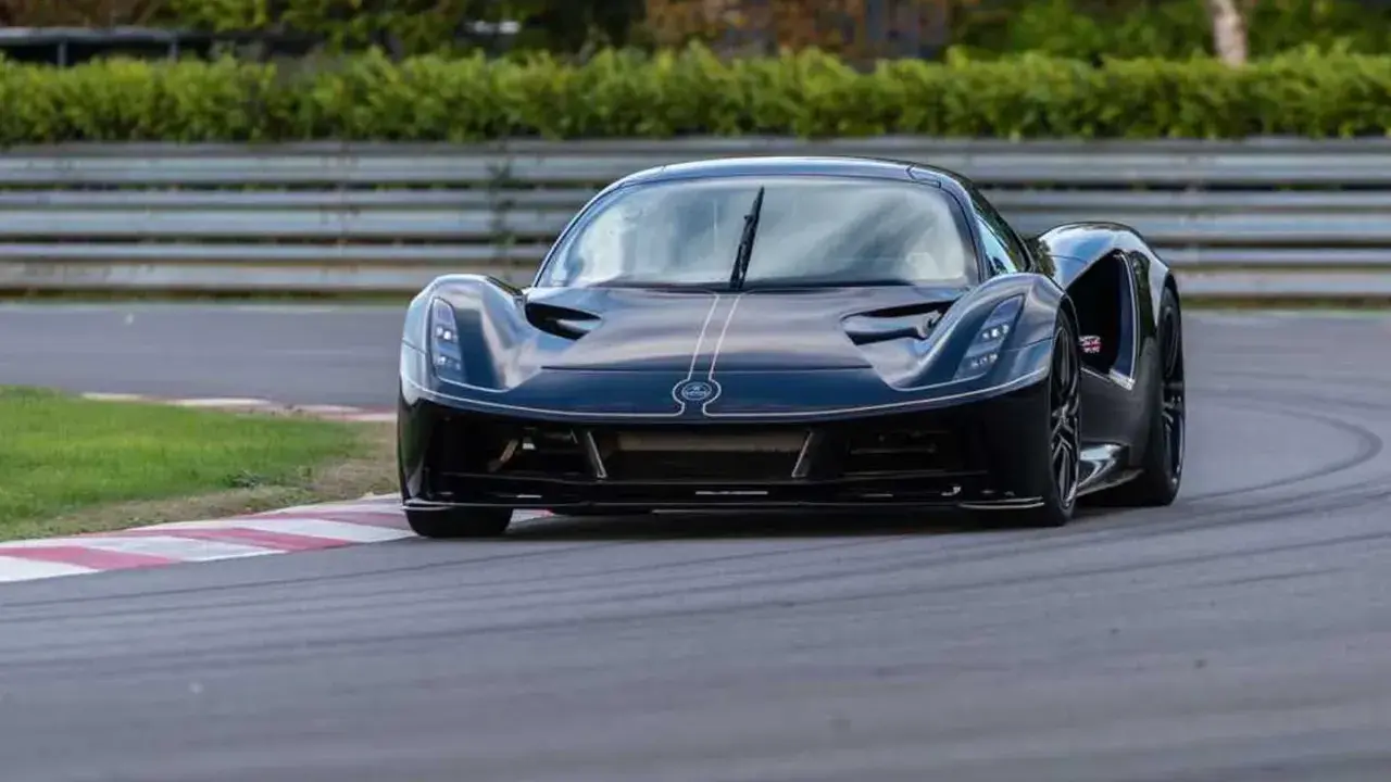 La Lotus Evija nera sfreccia su una pista, con un'aria di potenza e velocità.