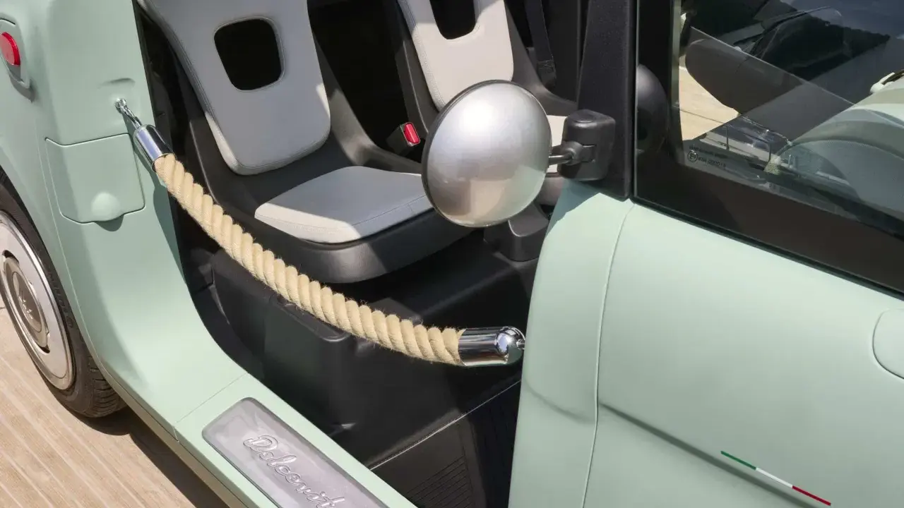 Interni Fiat Topolino: sedili chiari, corda decorativa e logo "Dolcevita" sulla soglia.