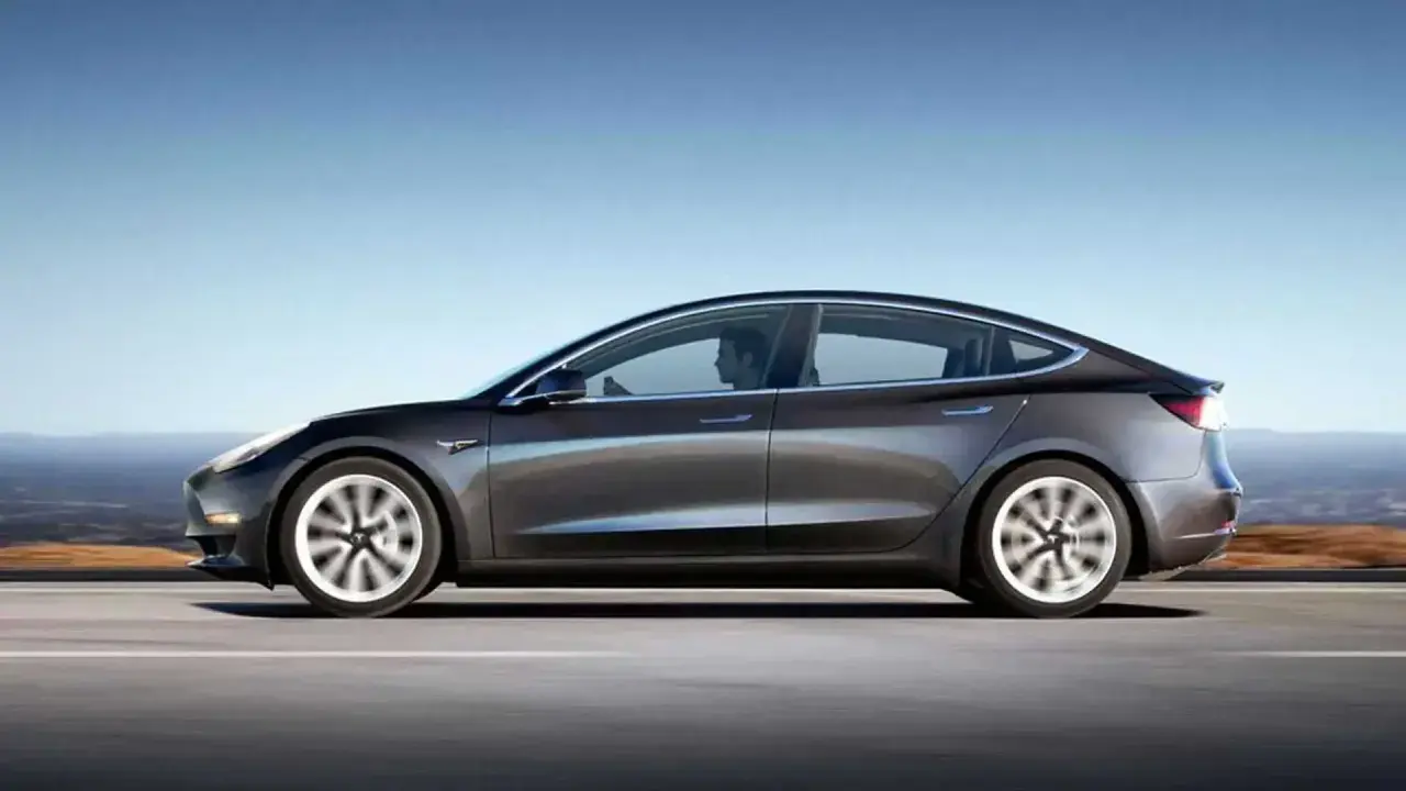 Tesla grigia in movimento su strada, con un conducente al volante. Quanti km fa una Tesla? Dipende dal modello e dalla batteria.
