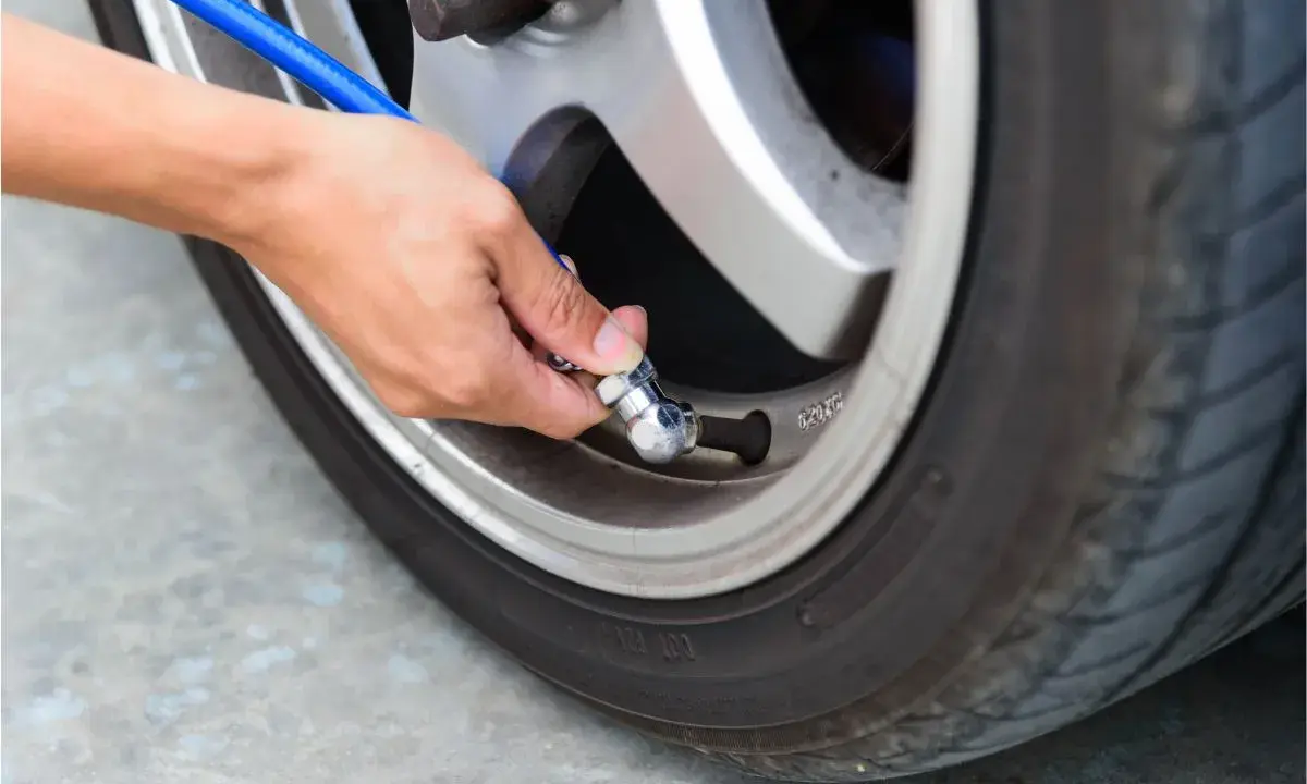 Mano che collega un tubo blu alla valvola per gonfiare gomme auto.