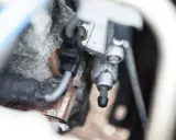 Dettaglio del cilindretto frizione, utile per capire come spurgare pompa frizione. Si notano tubi e parti metalliche arrugginite.