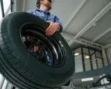 Meccanico con un nuovo pneumatico, pronto per il cambio gomme estive.
