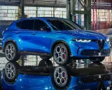 Alfa Romeo Tonale blu, un esempio di stellantis auto elettriche, riflette sul pavimento bagnato di un capannone industriale.