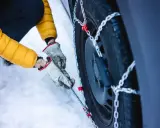 Mani guantate montano le catene da neve su una gomma 4 stagioni. Se ho le gomme 4 stagioni devo avere le catene per la sicurezza invernale.