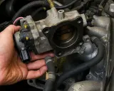 Mano che tiene il corpo farfallato, componente essenziale per il controllo del motore.