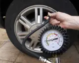 Controllo della pressione gomme auto con manometro. La lancetta indica un valore basso, suggerendo la necessità di gonfiare.