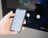 Mano che usa smartphone con mappa per trovare stazione di ricarica. L'app mostra la posizione e le opzioni per monitorare la carica.