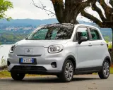 Leapmotor T03, un'auto elettrica grigia parcheggiata vicino a un lago, pronta per un viaggio con la sua eccellente autonomia.