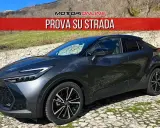 Toyota C-HR grigia parcheggiata su un selciato, con la scritta "PROVA SU STRADA". La sua linea moderna suscita un senso di delusione per chi si aspettava di più.