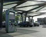 Moderne colonnine ricarica auto elettriche sotto una pensilina con pannelli solari. Diverse auto in carica.