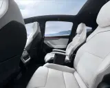 Interni bianchi e neri del Tesla Model Y, con sedili in pelle, tetto panoramico e vista sulle montagne.