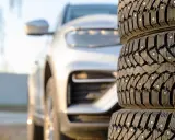 Gomme chiodate in primo piano, con un'auto bianca sfocata sullo sfondo. Mi chiedo se posso montare gomme con altezza diversa per affrontare ogni tipo di terreno.
