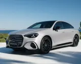 La Mercedes Classe C 2026, un'elegante berlina elettrica, si presenta con un design moderno e sportivo, con cerchi neri e uno sfondo marino.