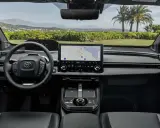 Interni moderni della Toyota bz4x con ampio display centrale e volante multifunzione. Navigazione attiva per un viaggio panoramico.