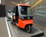 Un vivace Fiat Tris arancione e grigio, un veicolo a tre ruote per il trasporto merci, esposto su una pedana.