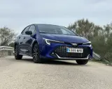 Toyota Corolla blu parcheggiata su strada sterrata, con vegetazione sullo sfondo. Un'auto che offre diverse motorizzazioni.