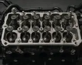 Dettaglio di un motore con punterie e valvole in primo piano. Componenti meccanici essenziali per il funzionamento del motore.