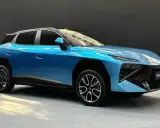 Un'elegante Omoda 4 blu metallizzato, con un design futuristico e cerchi in lega sportivi, si presenta su un pavimento grigio.