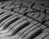 Primo piano del battistrada di uno pneumatico, con dettagli sulle scanalature e sui blocchi. Si intravede l'indice di carico pneumatici.
