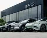 Vari modelli di auto BYD parcheggiati davanti a uno showroom moderno.
