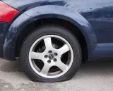Ruota posteriore di un'auto blu con evidente perdita pressione pneumatici. Il coprimozzo riporta il logo "Borbet".