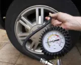 Controllo della pressione delle gomme auto con manometro. La lancetta indica circa 2 bar.