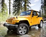 Jeep Wrangler 2.8 CRD in giallo, immerso in un ruscello tra alberi. Un'avventura che potrebbe presentare qualche problema.