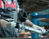 Meccanico con guanti bianchi tiene un nuovo sterzo macchina, pronto per l'installazione.