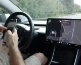 Mani sul volante, ma lo sguardo è sullo smartphone mentre il **Tesla Autopilot** guida. Navigazione e musica sul grande schermo.