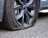 Gomma bucata dell'auto, sgonfia e appoggiata sull'asfalto. Un inconveniente che ferma ogni viaggio.