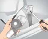 Mani che smontano un motorino del finestrino elettrico, un cacciavite che svita una vite. Guida per capire come alzare manualmente finestrino elettrico.