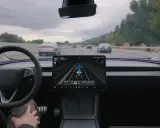 Interno di una Tesla con il sistema FSD attivo, mostra la guida autonoma in autostrada con visualizzazione delle auto circostanti.