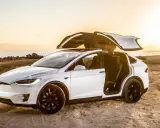 Tesla Model X bianca con portiere ad ali di gabbiano aperte al tramonto, un'auto elettrica che rappresenta il lusso e l'innovazione, forse la tesla più costosa.