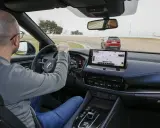 Uomo al volante su una pista, con un'altra auto rossa davanti. Il navigatore mostra il "Circuito del Jarama", ideale per chi vuole aumentare cavalli auto.